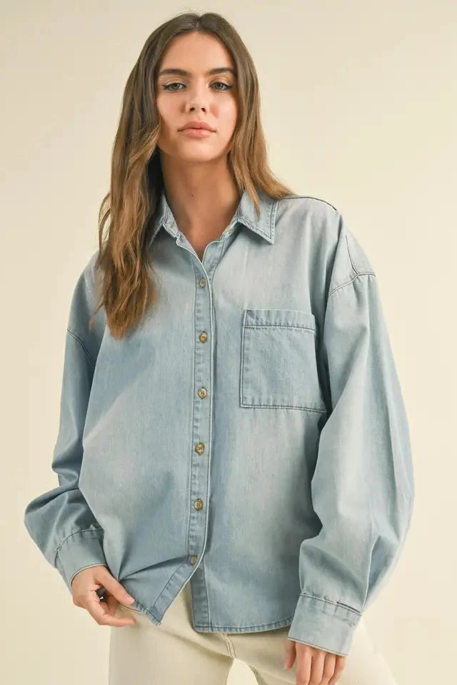 Woman wearing a light blue denim shirt against a beige background