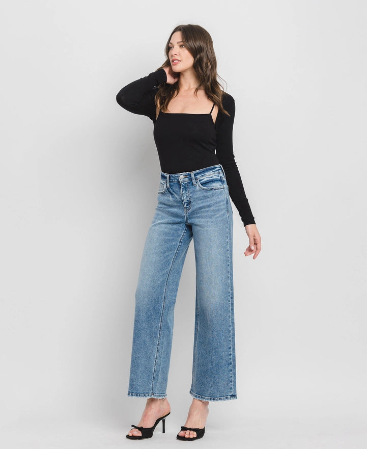 Woman wearing a black top and blue jeans on a white background