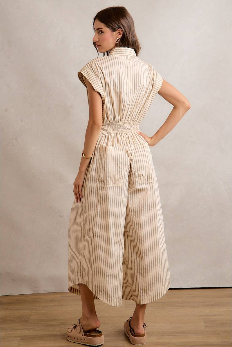 Woman wearing a beige and white striped dress against a plain background