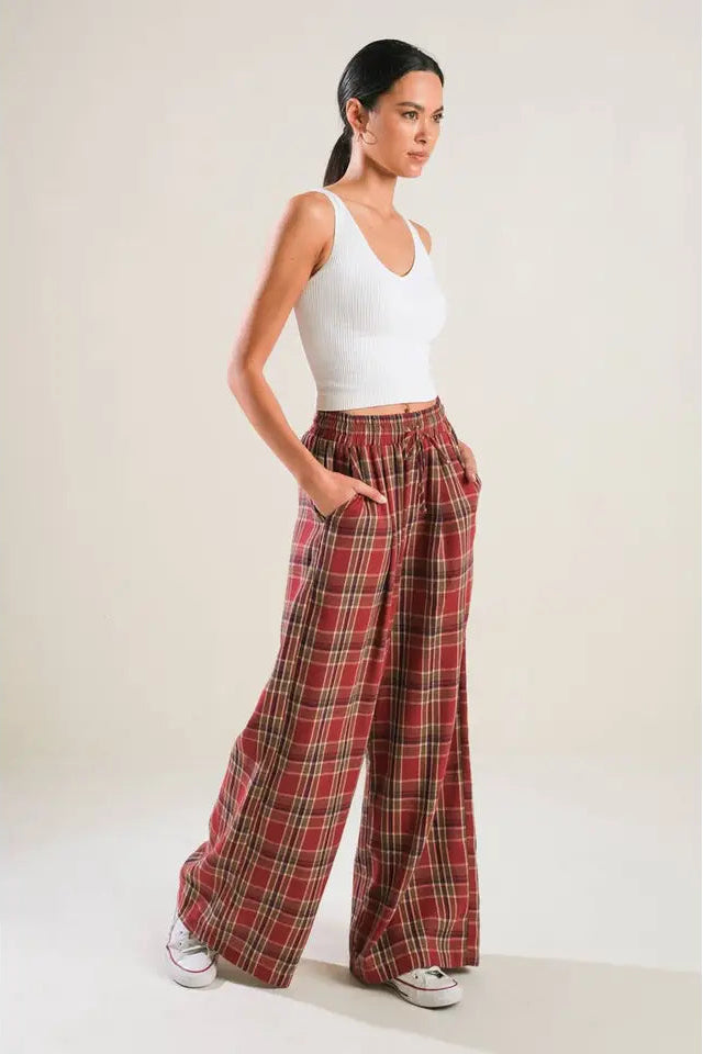 Woman wearing a white top and red plaid pants against a plain background