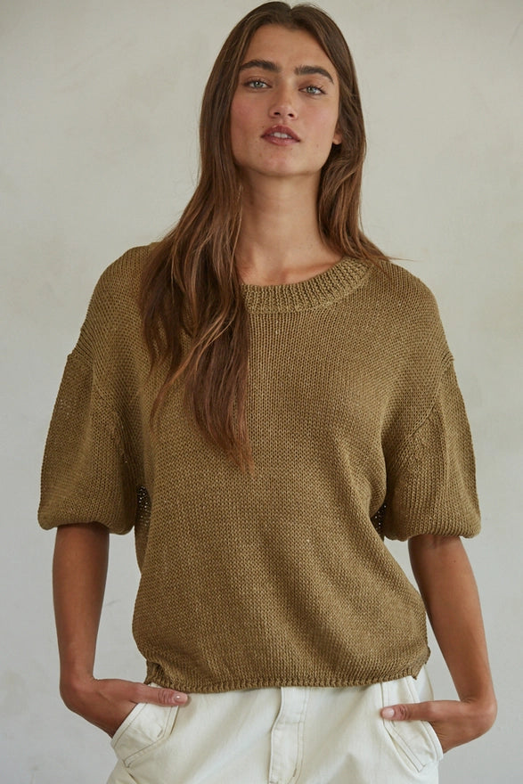 Woman wearing a mustard yellow sweater against a plain background