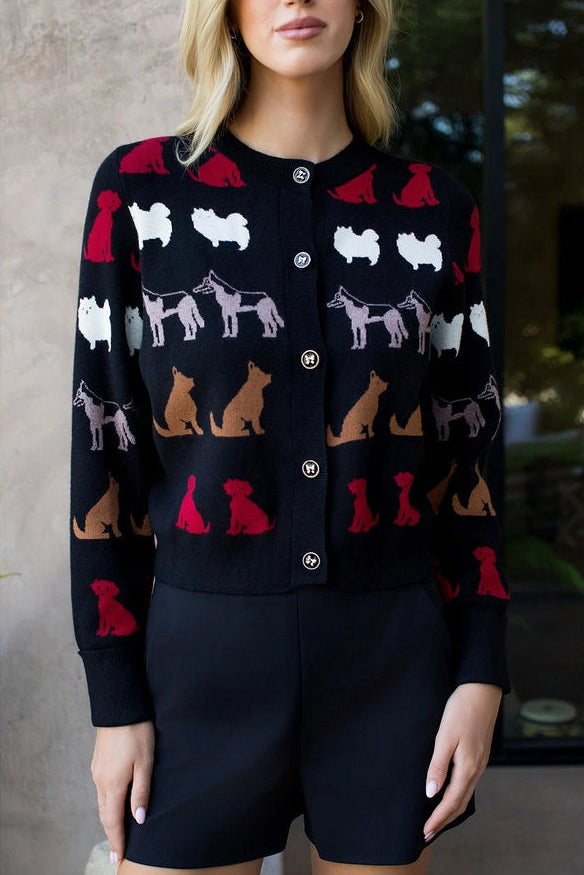 Woman wearing a black cardigan with colorful dog pattern against a neutral background