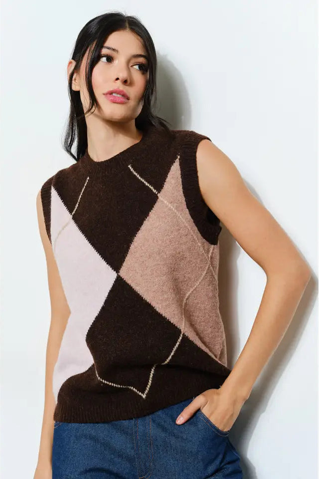 Woman wearing a sleeveless, argyle-patterned sweater against a light background