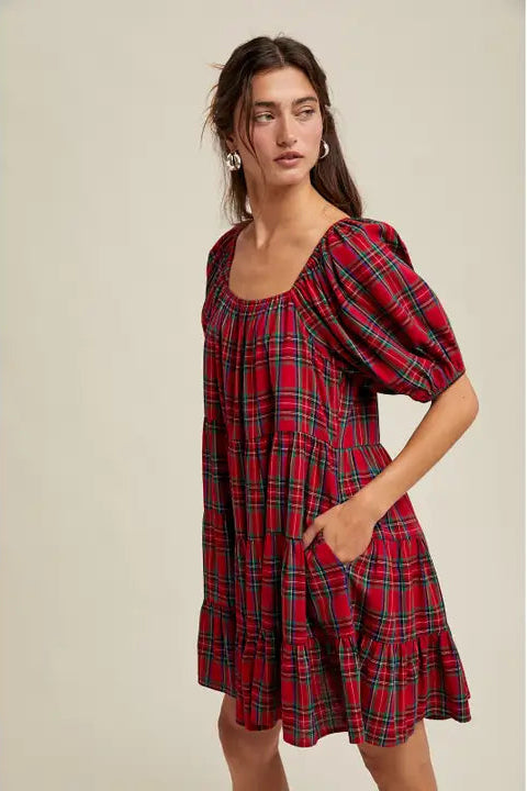 Woman wearing a red plaid dress against a neutral background