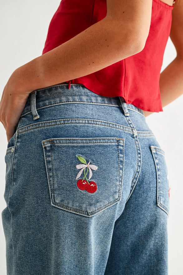 Blue jeans with a cherry patch on the back pocket against a white background