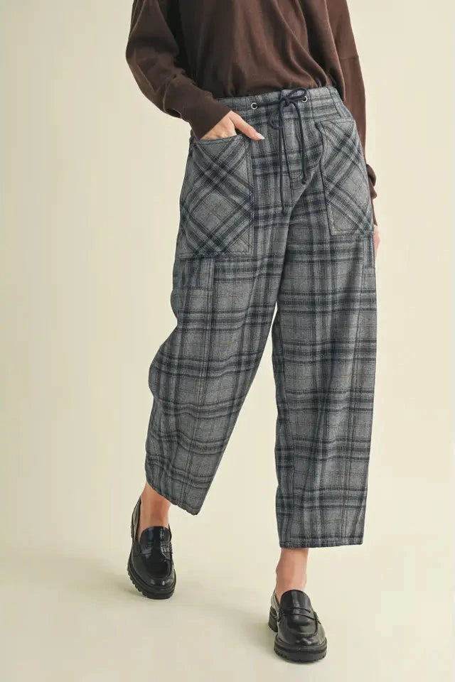Person wearing plaid pants and a brown top on a beige background