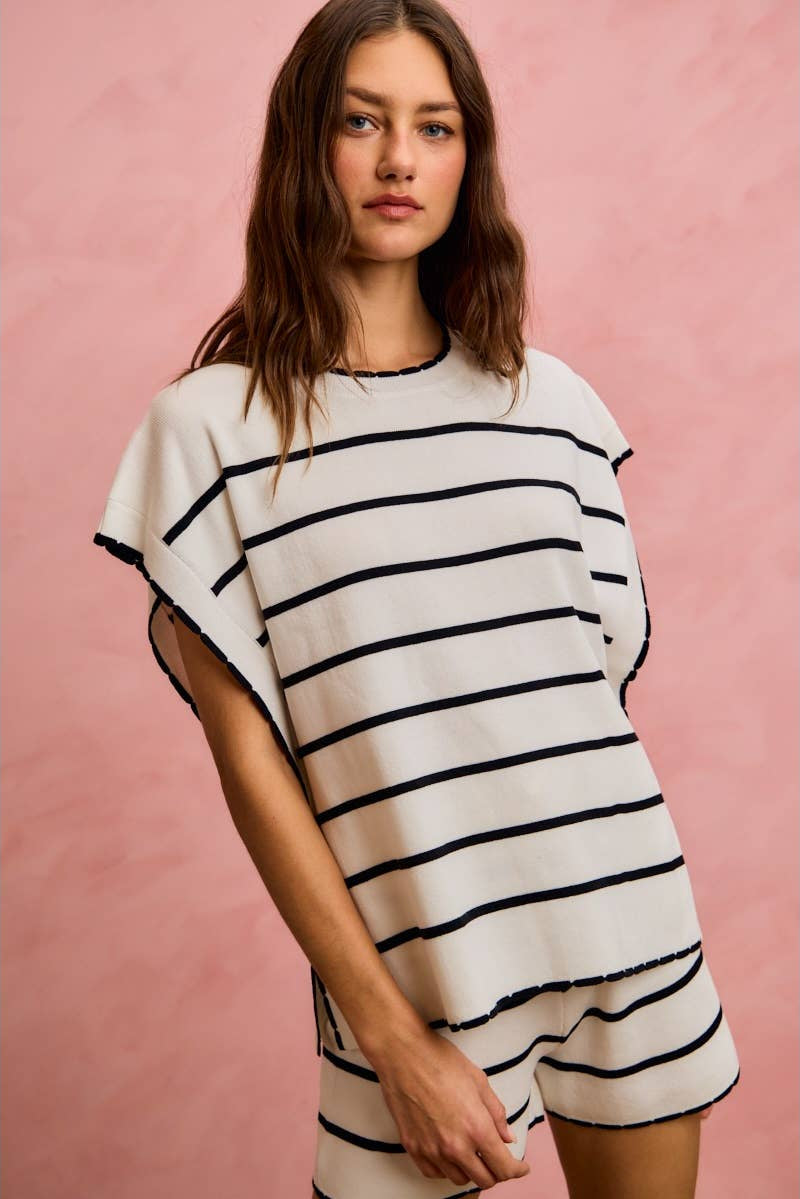 Woman wearing a white and black striped dress against a pink background