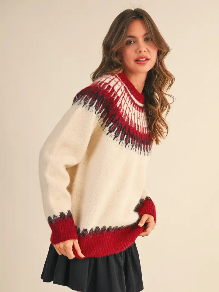 Woman wearing a cream sweater with red and black pattern on a beige background