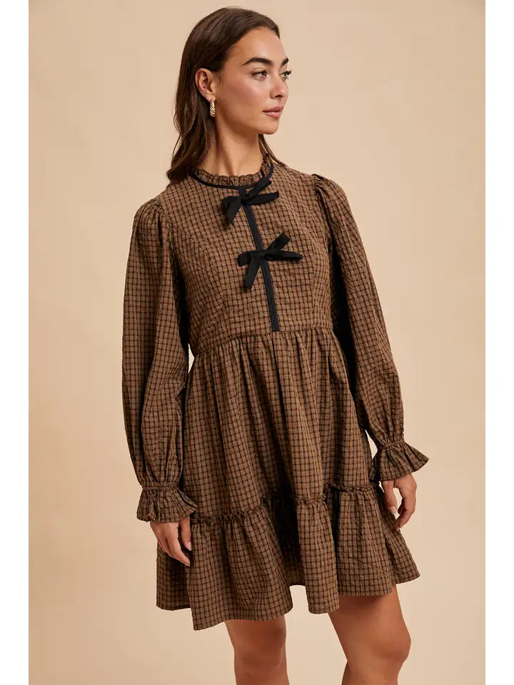 Woman wearing a brown checkered dress with black bows on a beige background