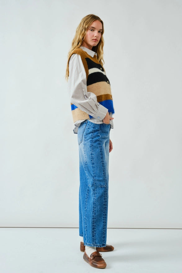 Person wearing a colorful sweater and blue jeans against a white background