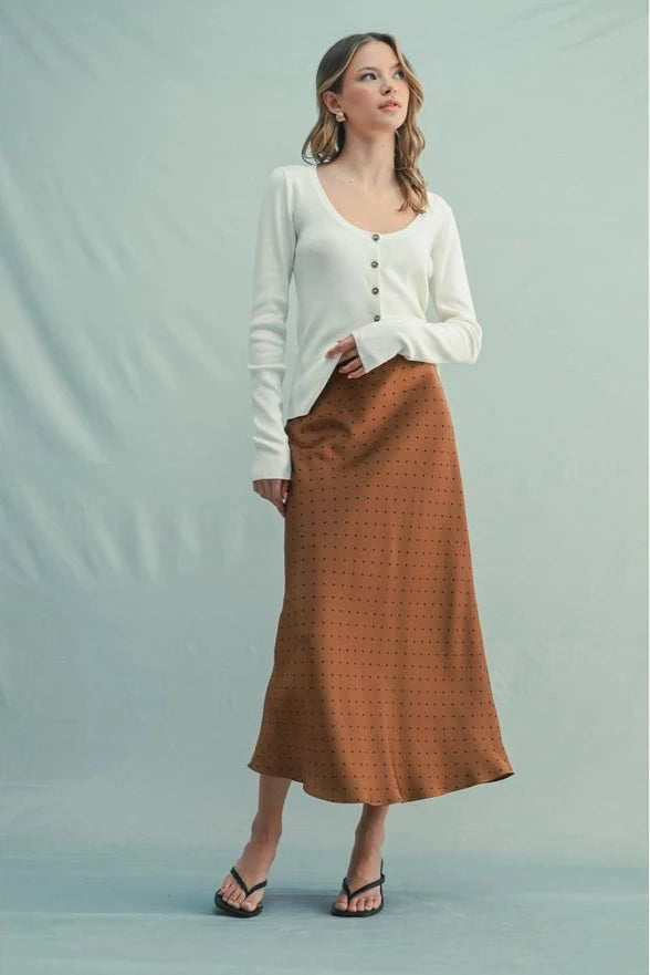Woman wearing a white blouse and brown skirt against a light green background