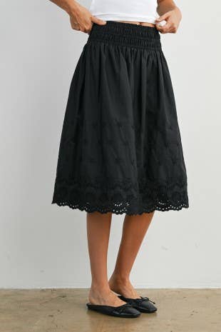 Black lace skirt worn by a person on a plain background