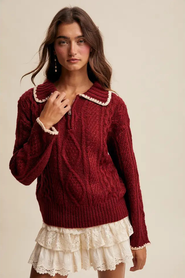 Woman wearing a burgundy sweater with lace trim on a beige background