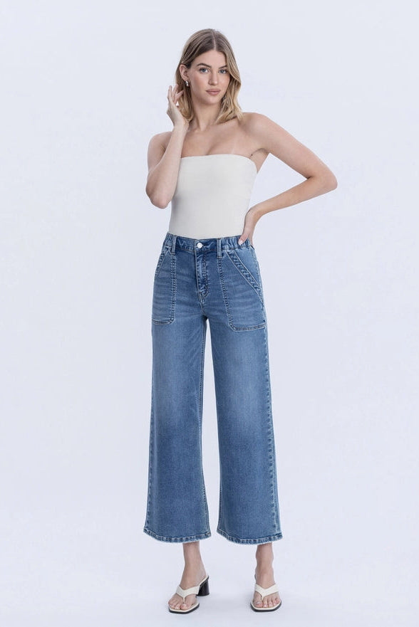 Woman wearing a white strapless top and blue jeans on a white background