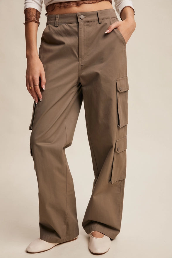 Girl wearing mocha colored cargo pants on plain background.