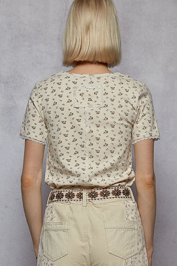 Person wearing a patterned shirt and beige pants against a gray background