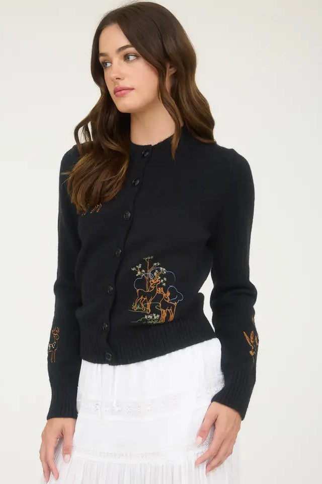 Woman wearing a black cardigan with embroidery on a white background