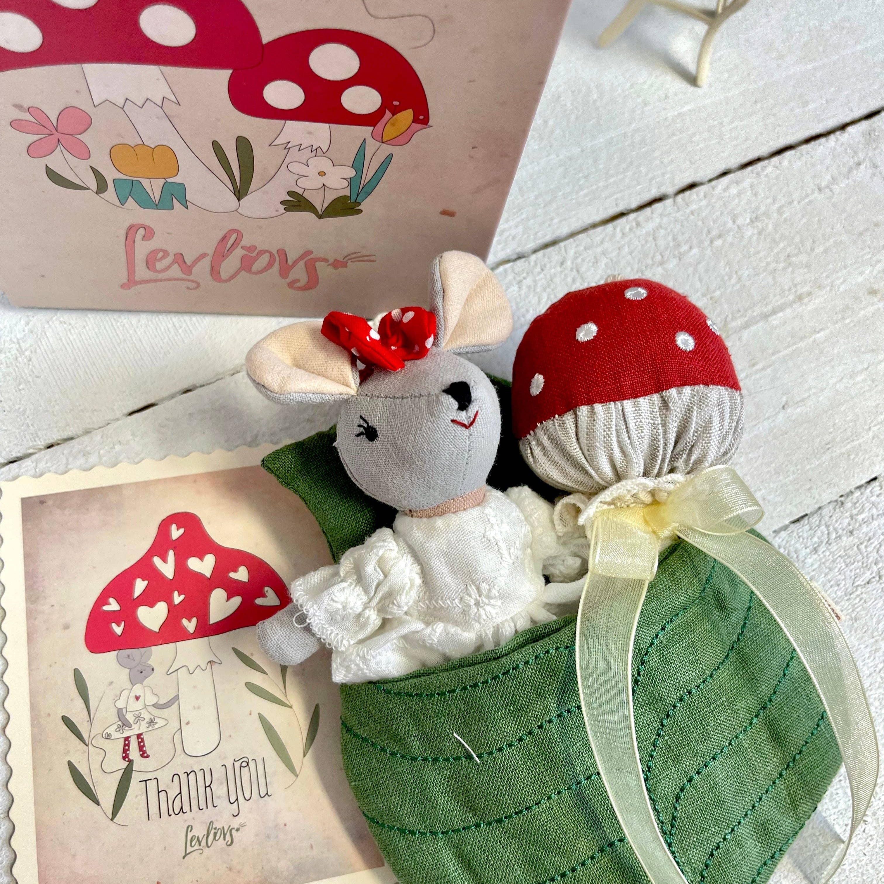 Two small plush toys resembling mushrooms and a rabbit, with a 'thank you' card in the background.