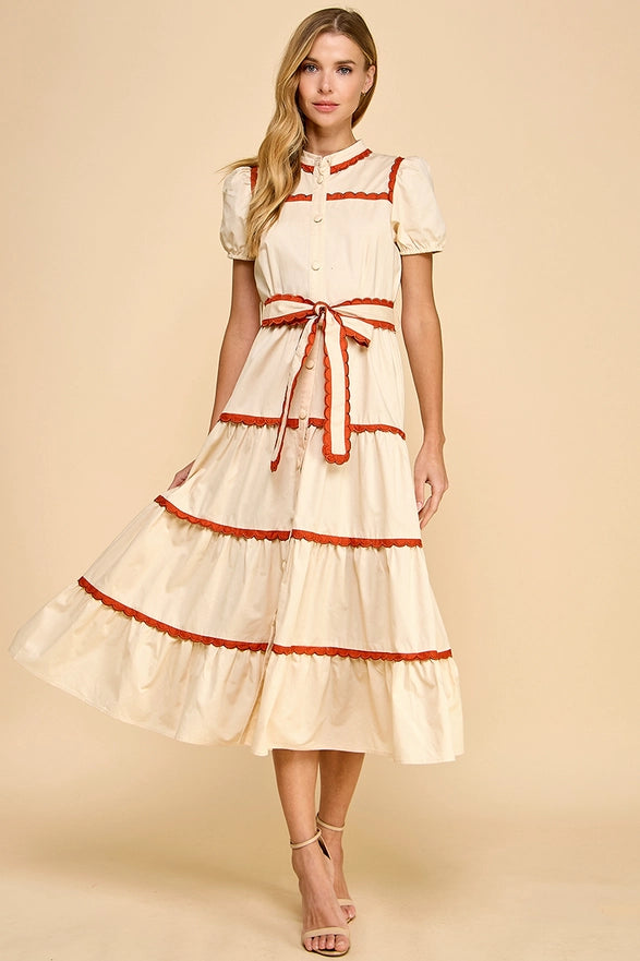 Woman wearing a cream dress with red trim on a beige background