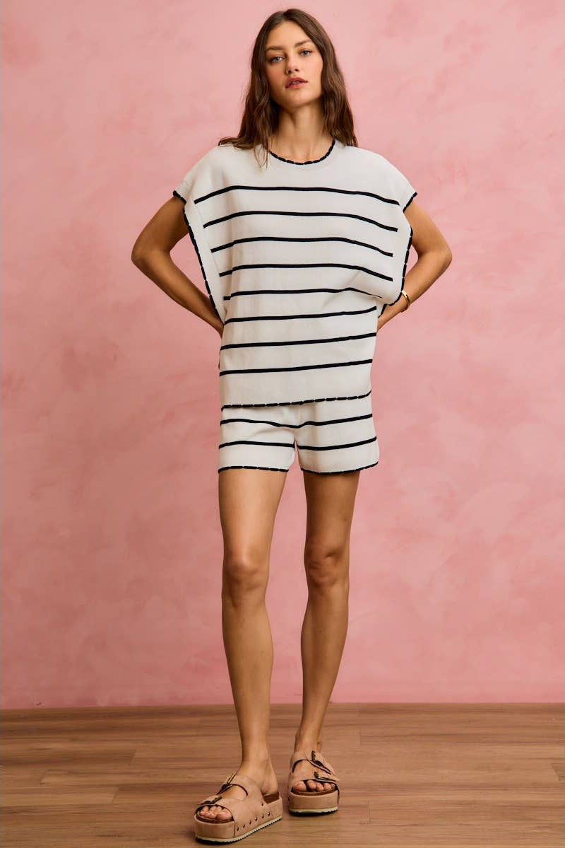 Woman wearing a black and white striped outfit against a pink background
