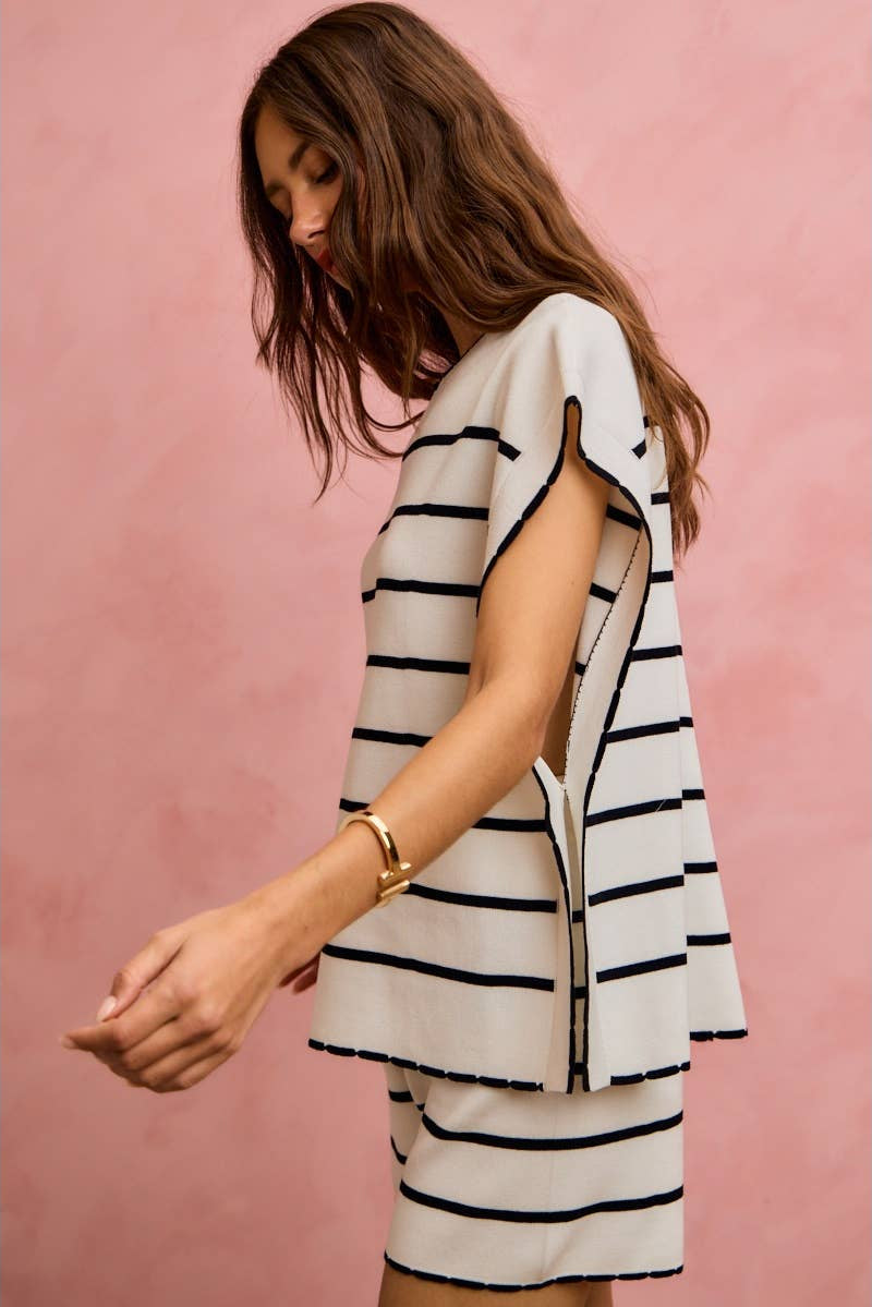 Woman wearing a black and white striped outfit against a pink background