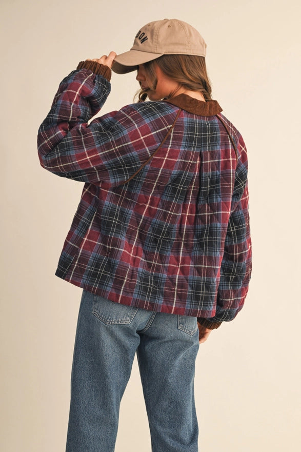 Person wearing a plaid shirt and jeans with a beige cap on a plain background