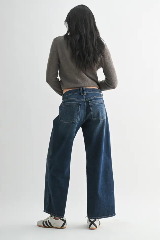 Person wearing blue jeans and a gray sweater on a plain background