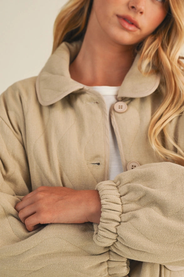 Person wearing a beige coat with a neutral background