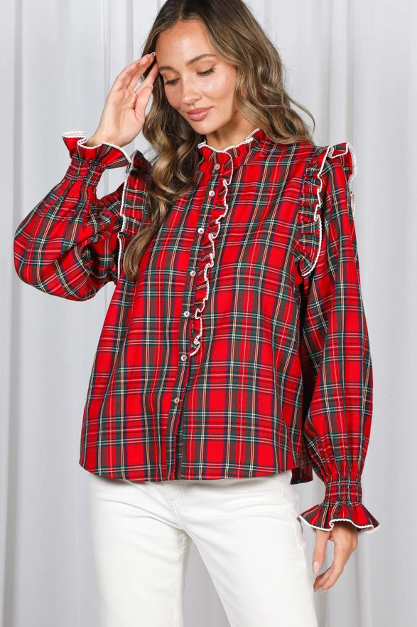 Woman wearing a red plaid blouse with ruffled sleeves against a white background