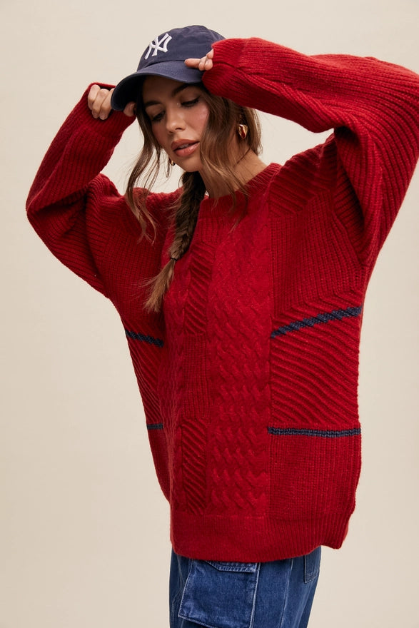 Woman standing against a plain background wearing a Red pull over sweater