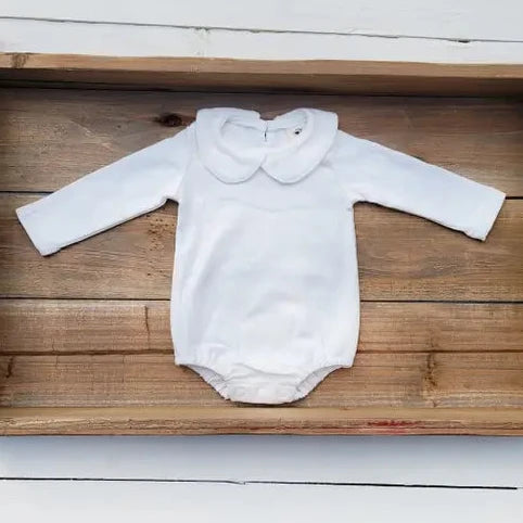 White baby onesie on a wooden tray with a white background