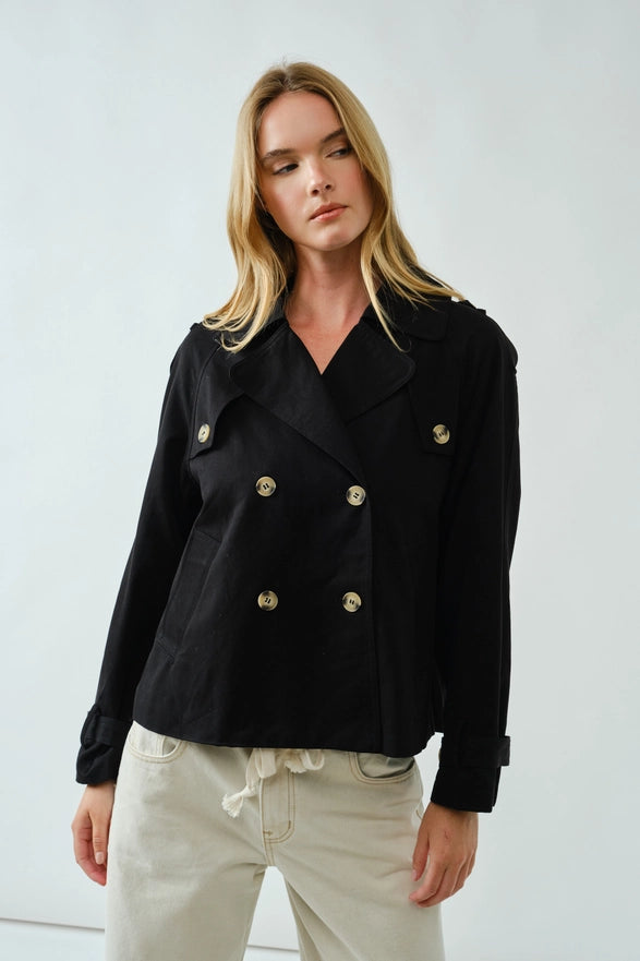 Woman wearing a black jacket with gold buttons on a white background