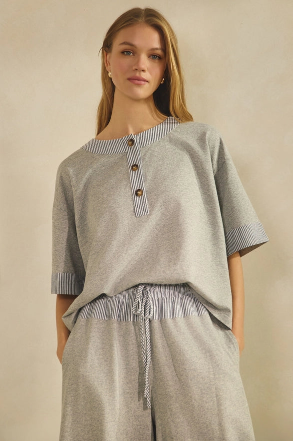 Woman wearing a gray outfit with striped details on a beige background