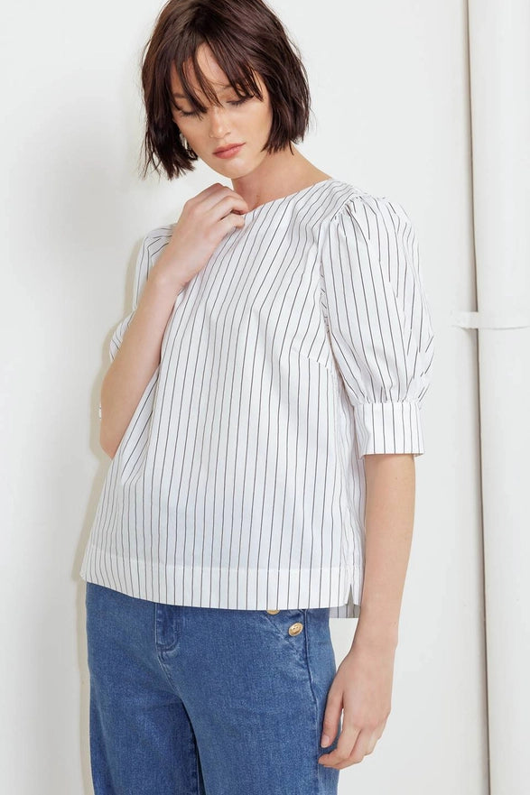 Woman wearing a white and gray striped blouse and blue jeans against a white background