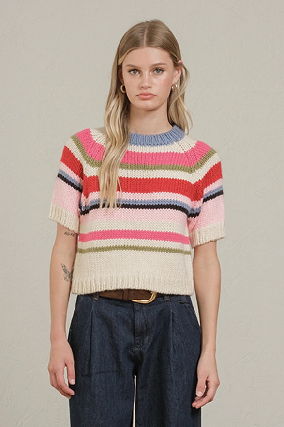 Woman wearing a colorful striped sweater against a plain background