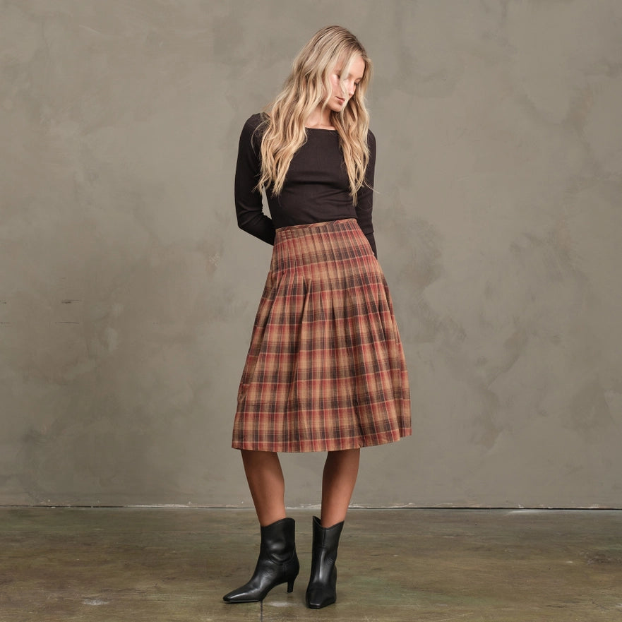 Woman wearing a plaid skirt and black top against a plain background