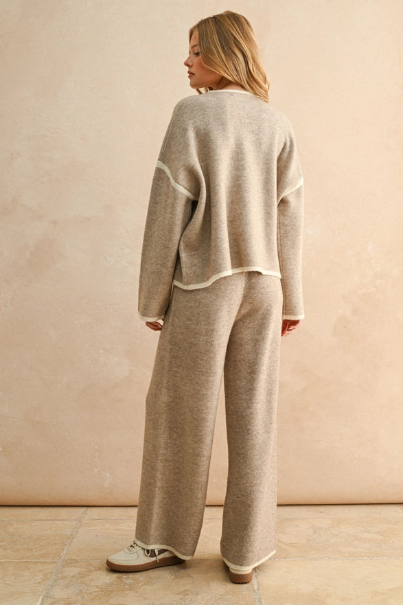 Woman wearing a beige sweater and pants set against a plain background