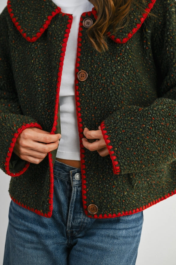 Green jacket with red trim worn by a person on a white background