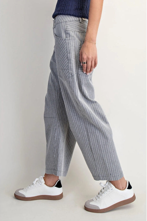 Person wearing gray striped pants and white sneakers on a plain background