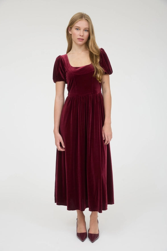 Woman wearing a burgundy velvet dress on a white background