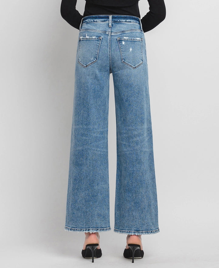 Blue wide-leg jeans worn by a person on a light gray background
