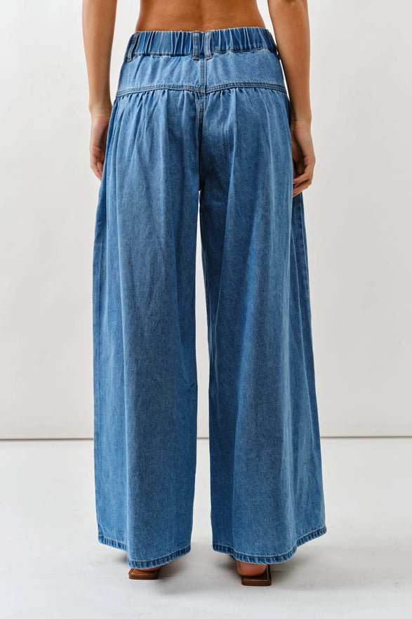 Blue denim wide-leg pants worn by a person on a white background