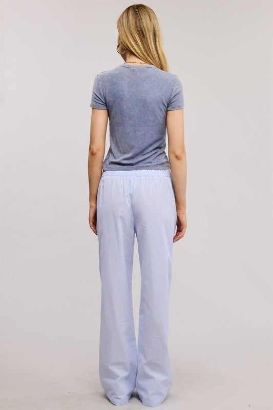 Person wearing a gray t-shirt and light blue pants on a plain background