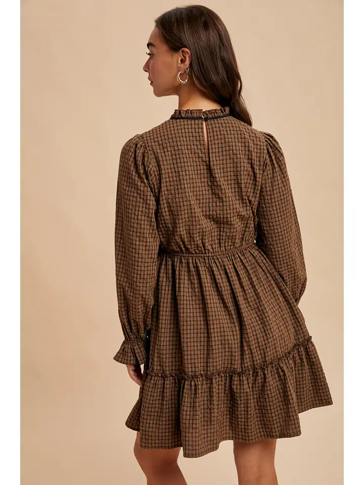 Woman wearing a brown checkered dress against a beige background