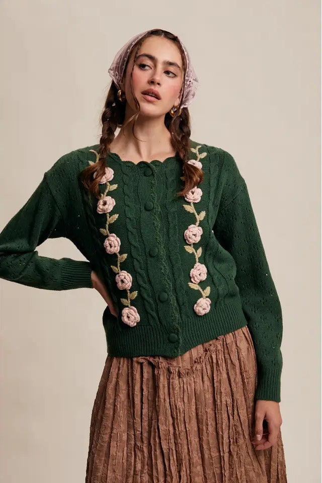 Woman wearing a green knitted cardigan with floral patterns on a beige background