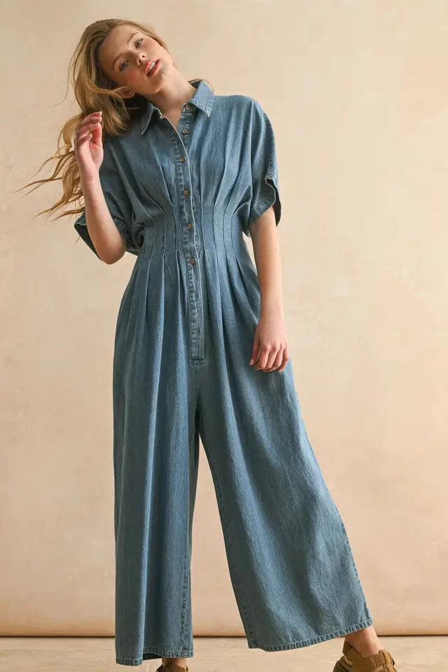 Woman wearing a denim jumpsuit against a beige background