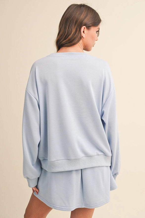 Light blue sweatshirt and shorts set on a beige background