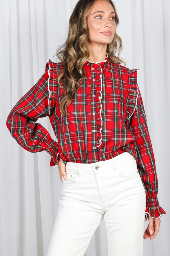 Woman wearing a red plaid shirt with white pants against a white background