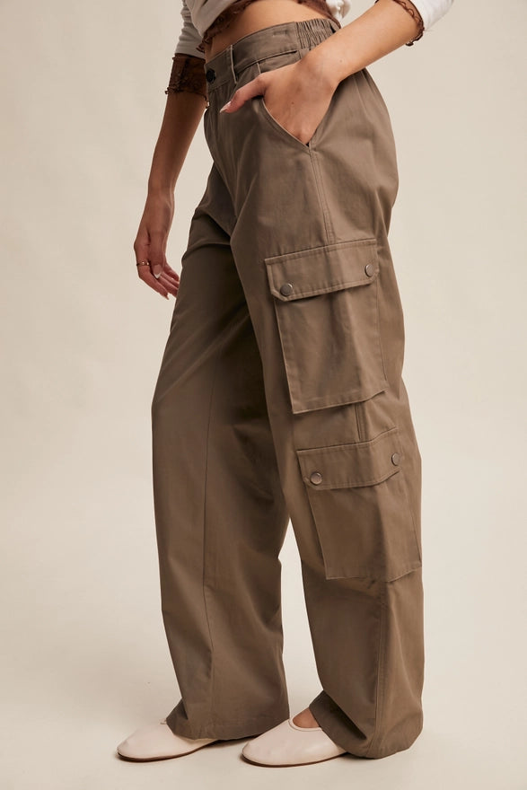 Girl wearing mocha colored cargo pants on plain background.