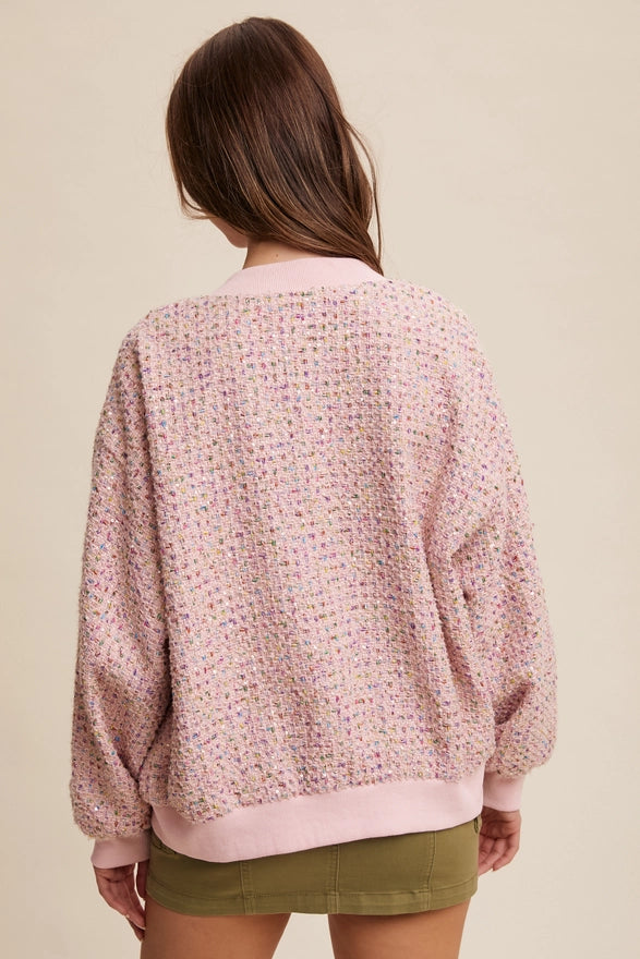 Person wearing a pink textured sweater and green shorts on a beige background